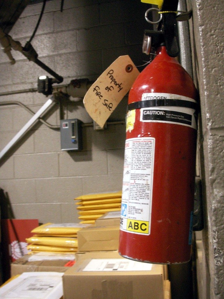 A red fire extinguisher with an inspection tag hanging beside it