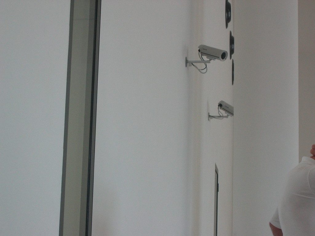Security cameras mounted high on a white interior wall